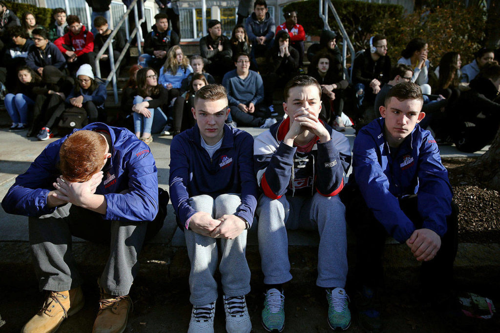 In this Feb. 28, 2018 photo, Somerville High School students sit on the sidewalk on Highland Avenue during a student walkout at the school in Somerville, Mass. A large-scale, coordinated demonstration is planned for Wednesday, March 14, when organizers have called for a 17-minute school walkout nationwide to protest gun violence. (Craig F. Walker/The Boston Globe via AP)
