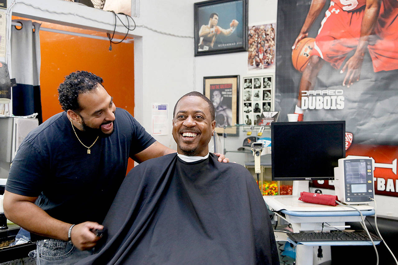 Barber Eric Muhammad (left), owner of A New You Barbershop, jokes with regular customer Marc M. Sims before measuring his blood pressure in Inglewood, California. Black male customers at dozens of Los Angeles area barbershops reduced one of their biggest health risks through a novel project that paired barbers and pharmacists to test and treat customers. (AP Photo/Damian Dovarganes)