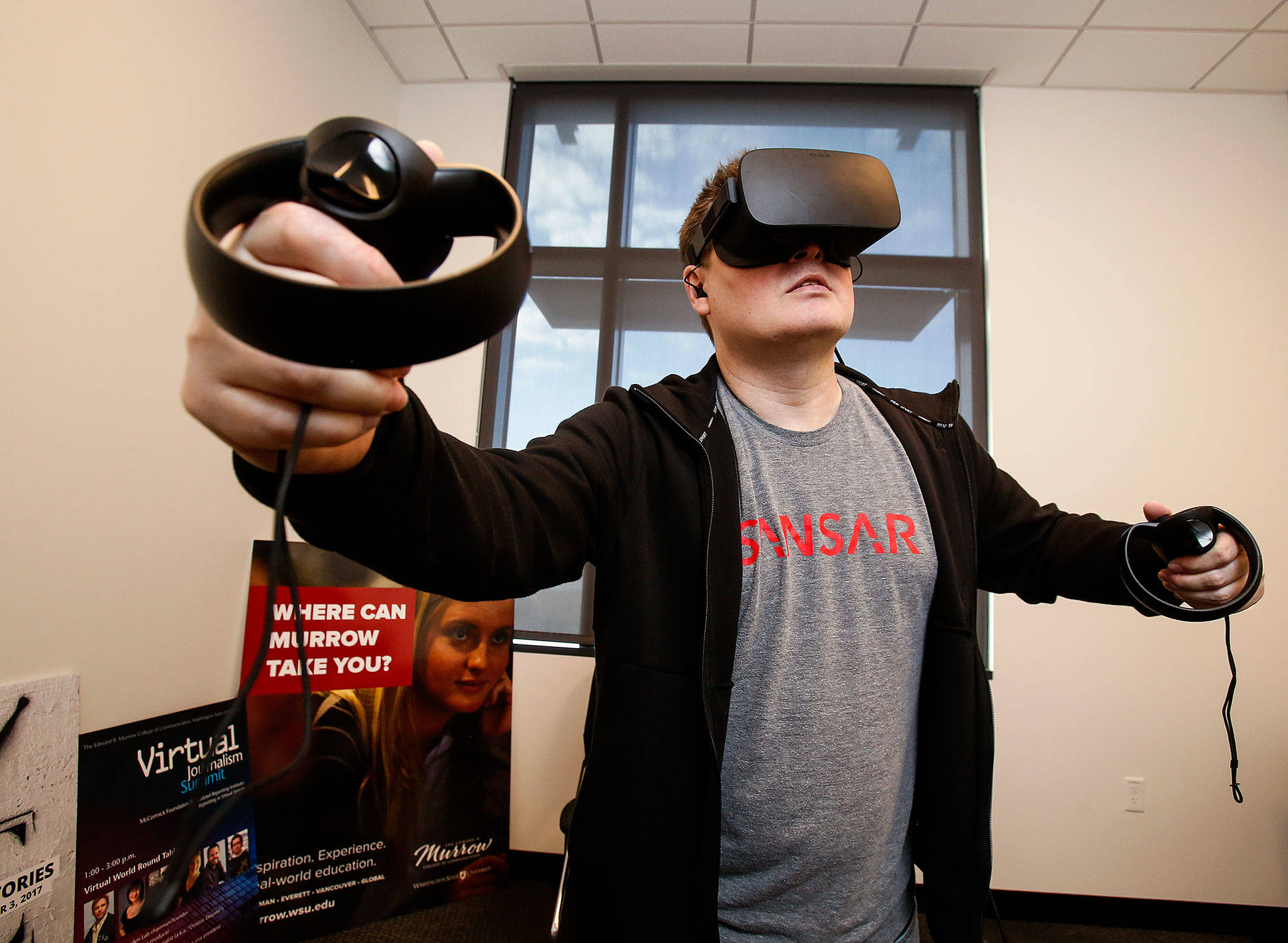 In his office at WSU Everett, clinical associate professor Brett Atwood, an expert with VR technology, dons an Oculus headset. (Dan Bates / The Herald)