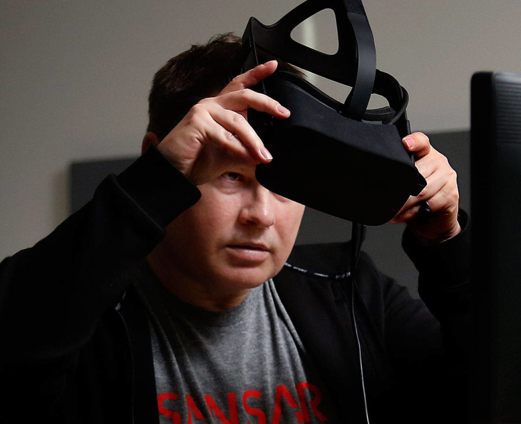 In his office at WSU Everett, clinical associate professor Brett Atwood, an expert with VR technology, dons an Oculus headset. (Dan Bates / The Herald)
