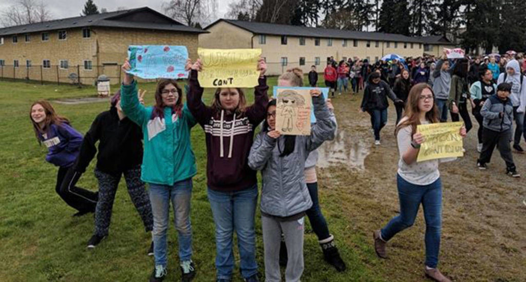 Marysville Middle School students hold up signs during a student-organized walkout to commemorate the Feb. 14 shooting deaths of 17 people at a high school in Florida. (Jake Martin)
