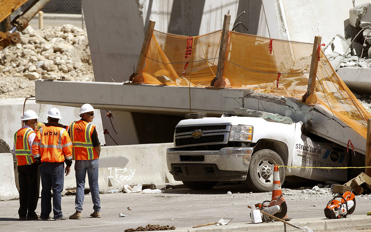 Workers stand next to a section of a collapsed pedestrian bridge on Friday near Florida International University in the Miami area. (AP Photo/Wilfredo Lee)