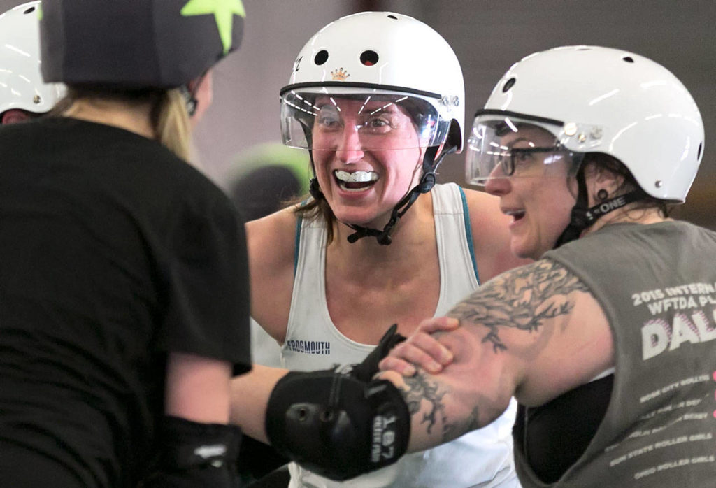 Lacey Ramon, (center) shares a smile in a defensive huddle Sunday afternoon during practice at Rat’s Nest in Shoreline on March 18, 2018. (Kevin Clark / The Daily Herald)
