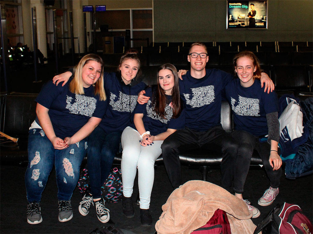 At Seattle-Tacoma International Airport, students from four Snohomish County high schools keep company while awaiting a flight to Washington, D.C. They wear T-shirts printed with school gun-violence victims’ names shaped as the state of Washington. The young protesters joining the march are, (from left), Katie Dalton, Marysville Pilchuck; Mikaylah Himmelberger, Marysville Getchell; Bailey Thoms, Marysville Getchell; Tom Roe, Lakewood; and Jocelyn van der Put, Lake Stevens. (Photo courtesy Jocelyn van der Put)
