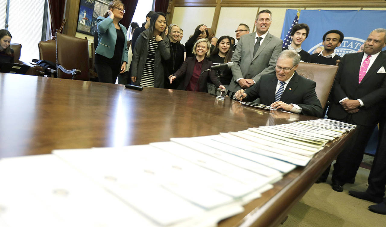 A long line of bills are placed on a table in the Governor’s conference room at the Capitol in Olympia on Wednesday, as Washington Gov. Jay Inslee begins a signing ceremony. (AP Photo/Ted S. Warren)