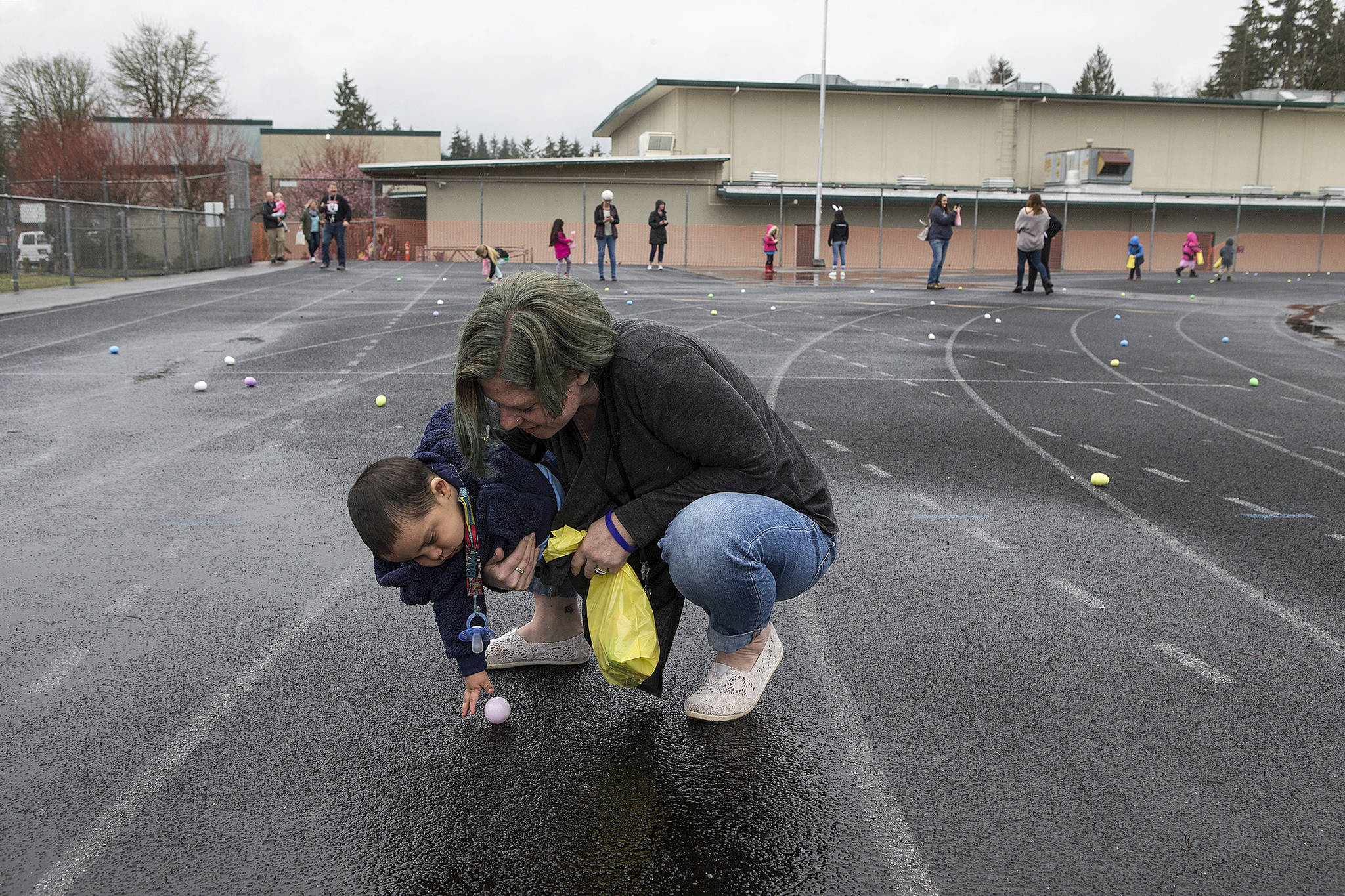 Andy Bronson / The Herald                                Nicole Lempke helps Giovanni Valentine grab an egg as they and other preschool students hunt for eggs on the track Thursday at Granite Falls Middle School. About 45 Granite Falls students organized a morning of activities, which included a petting zoo, games and the hunt.
