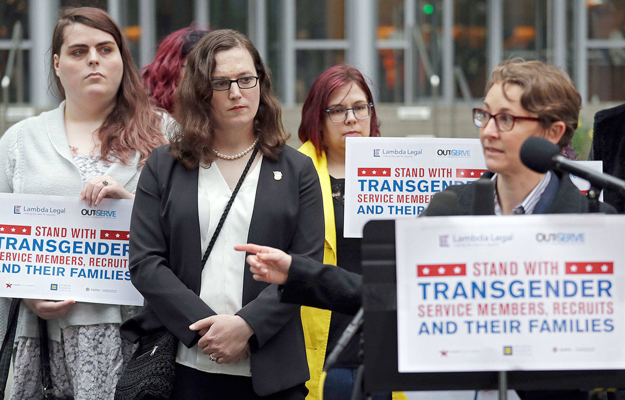 Plaintiff Cathrine Schmid (second left) listens as attorney Natalie Nardecchia speaks to reporters in front of the Seattle federal courthouse following a hearing Tuesday. U.S. District Judge Marsha Pechman says she won’t immediately consider President Donald Trump’s new policy banning transgender people from serving in the military. (AP Photo/Elaine Thompson)