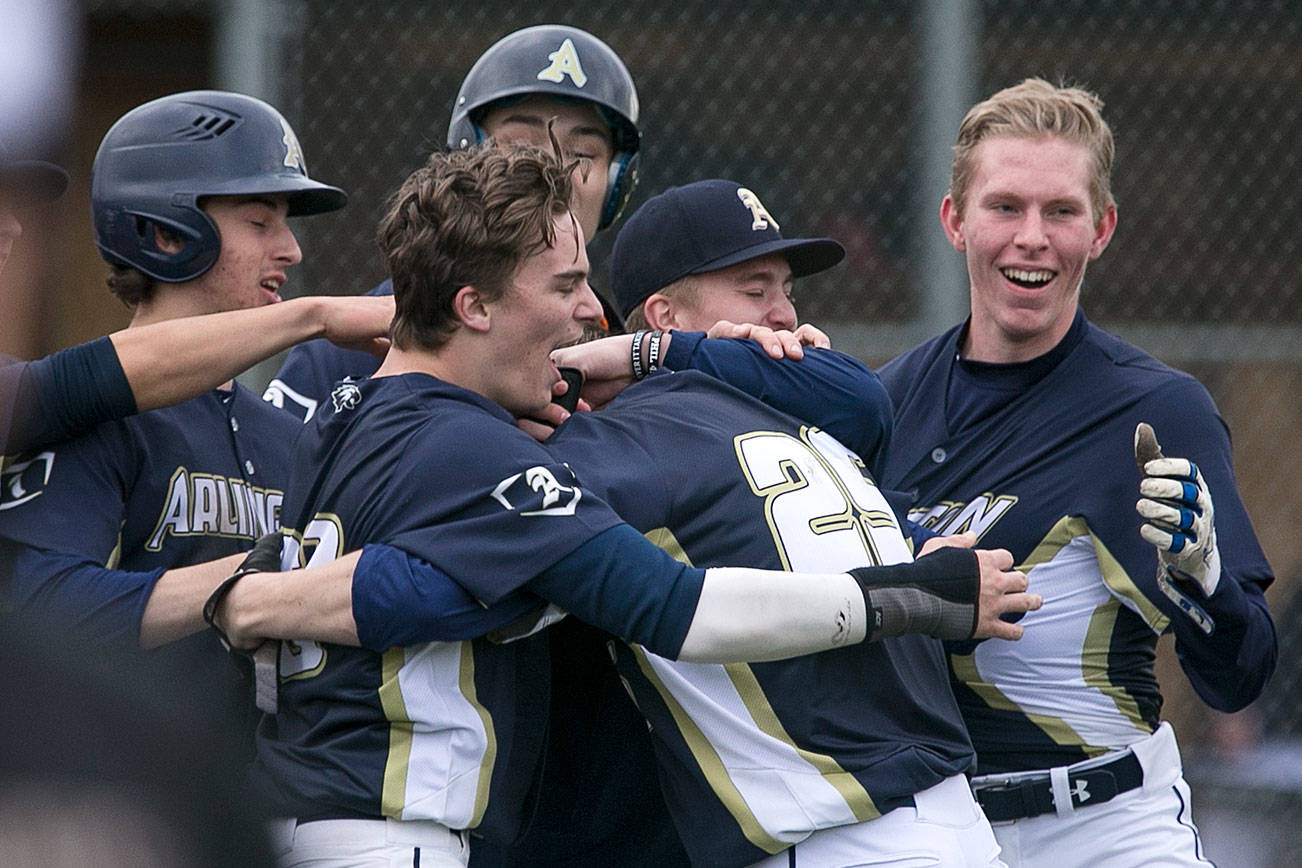 Arlington celebrates a Cameron Smith’s (25) game winning RBI at Arlington High School Wednesday afternoon in Arlington on March 28, 2018. Arlington won 6-5. (Kevin Clark / The Daily Herald)