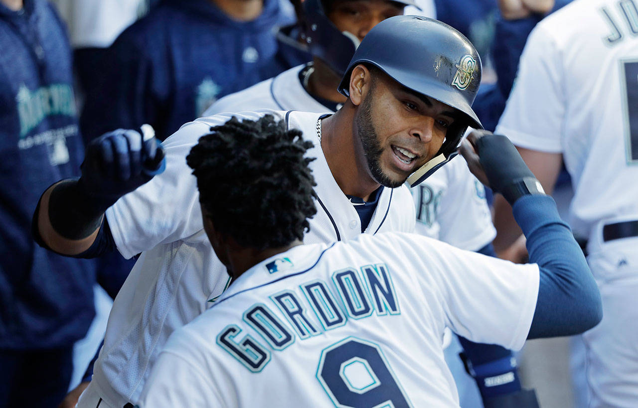 The Mariners’ Nelson Cruz (right) celebrates with Dee Gordon in the dugout after hitting a two-run home run against the Indians in the sixth inning of a game March 31, 2018, in Seattle. (AP Photo/Ted S. Warren)
