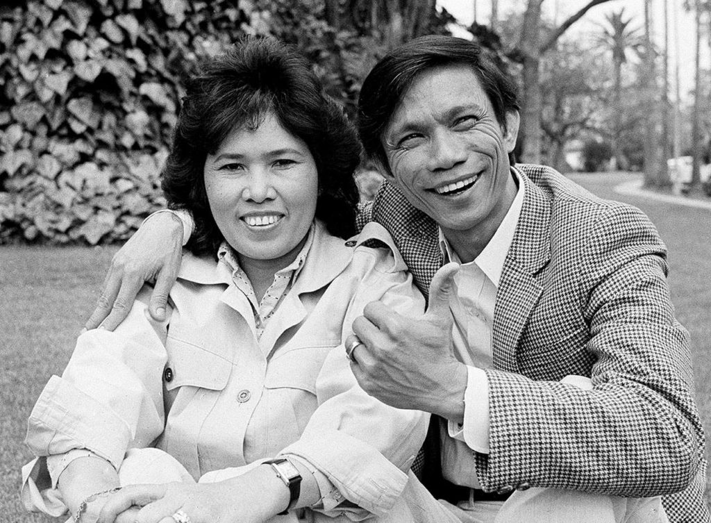 New York Times photographer Dith Pran sits with his wife, Ser Moeun, on the lawn outside the Beverly Hills Hotel on March 26, 1985. (AP Photo/Lennox McLendon, file)
