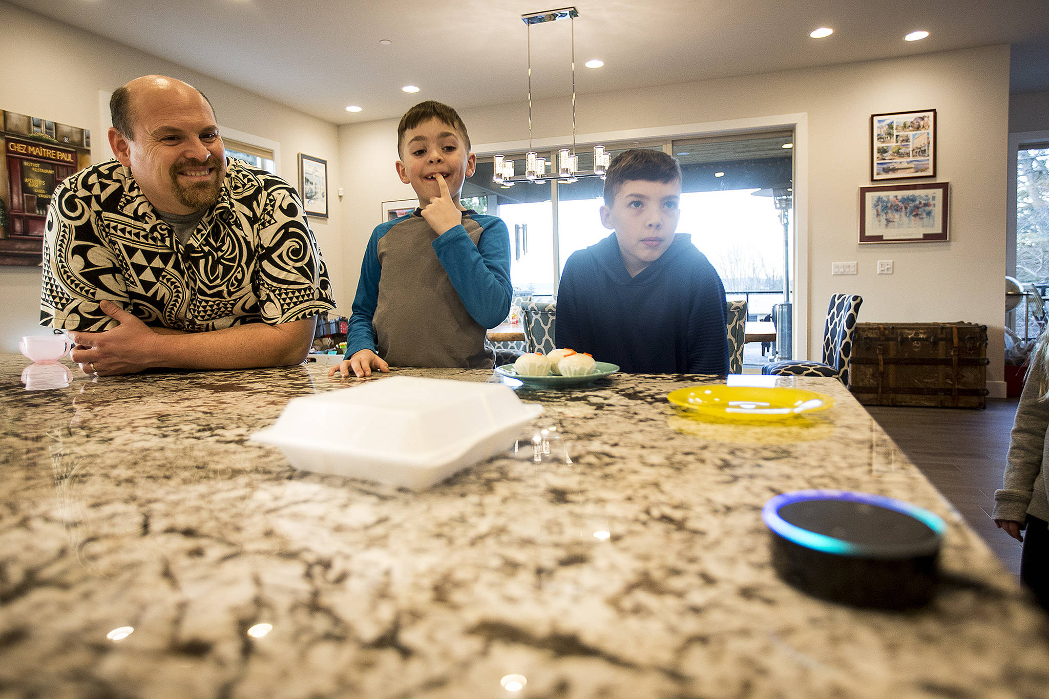Carlos Arguelles and his sons, Sebastian (center), 8, and Sam, 10, think of musical suggestions for Alexa, the robotic personality that helps users navigate Amazon Echo devices, at their home in Edmonds. The Arguelles family have incorporated seven into the design of their home. (Ian Terry / The Herald)