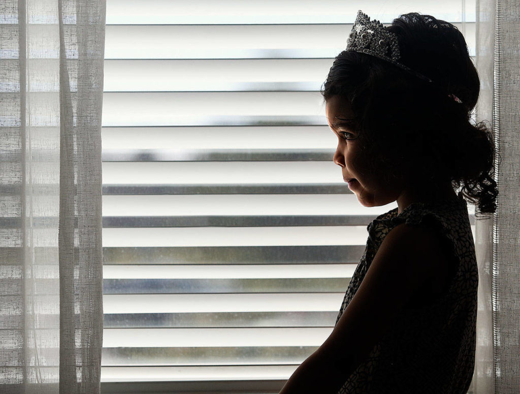 A springlike day finds 4-year-old Aria Hansen’s silhouette in a window, and it’s wearing a tiara. (Dan Bates / The Herald)
