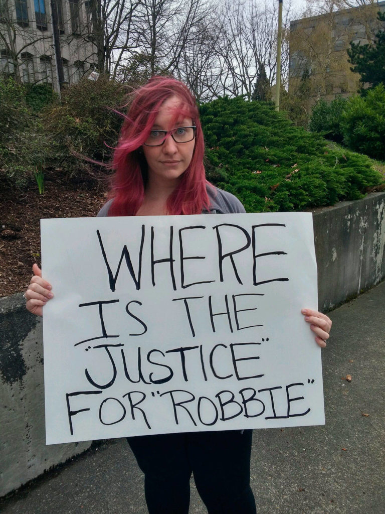 Protesters carrying signs assembled outside the Snohomish County Courthouse on Friday before the manslaughter sentencing of a teen who admitted causing the August death of Robert Myrick Jr., 16. (Rikki King / The Herald) 
