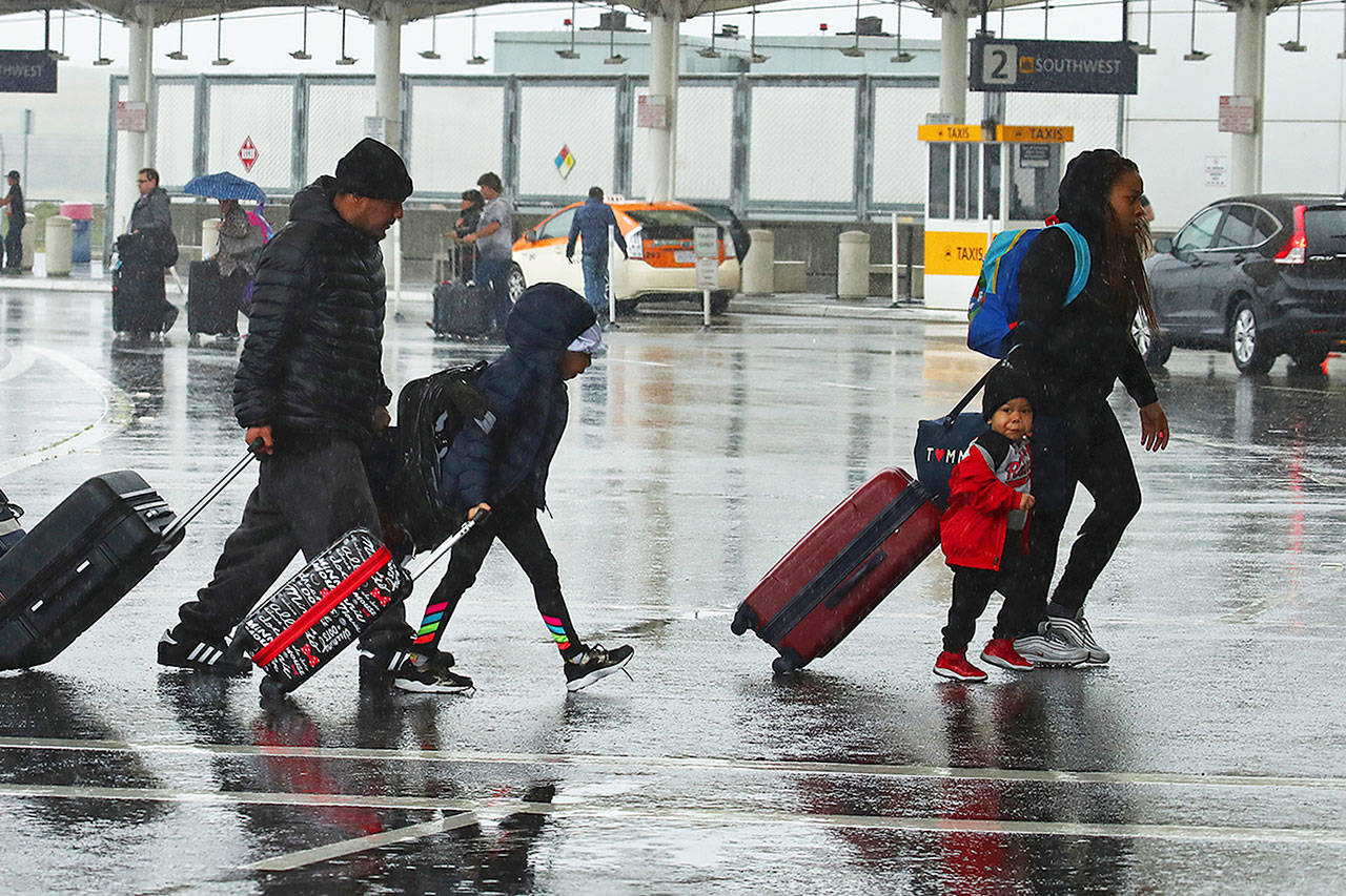 Travelers walk to the terminals at Oakland International Airport during a rain storm on Friday in Oakland, Calif. (Ben Margot / AP Photo)