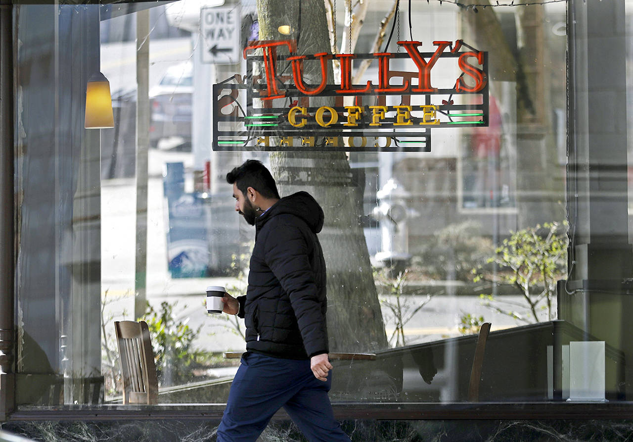A man walks past a Tully’s Coffee store in Tacoma. (Ted S. Warren / Associated Press)