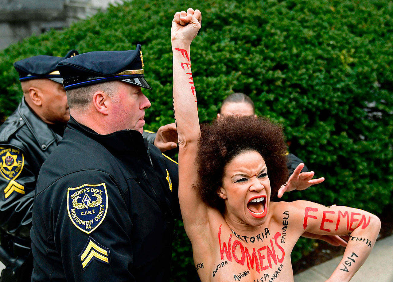 A protester is detained as Bill Cosby arrives for his sexual assault trial Monday at the Montgomery County Courthouse in Norristown, Pennsylvania. (AP Photo/Corey Perrine)