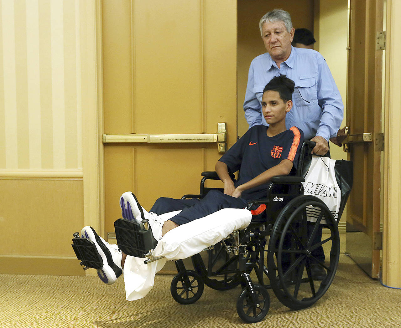 Anthony Borges is pushed by his grandfather Alfredo Borges at the start of a news conference in Plantation, Florida, on April 6. Borges sustained five bullet wounds after he used his body to block a classroom door during the shooting at Marjory Stoneman Douglas High School in Parkland, Florida. (AP Photo/Marta Lavandier)
