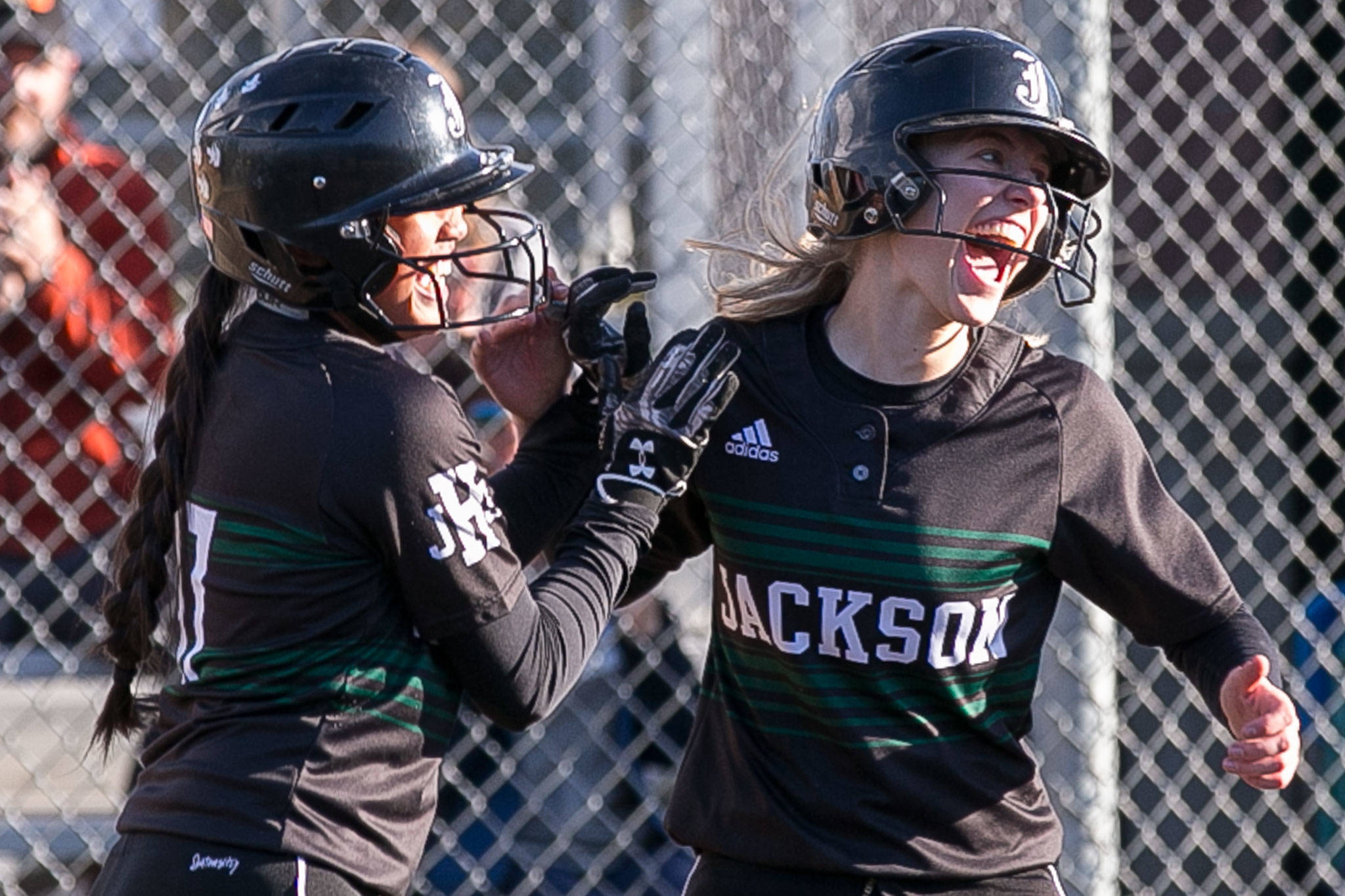 Jackson’s Braylin Jenson (left) and Jessica Asantor celebrate after the Timberwolves scored the winning runs in the ninth inning of a game against Lake Stevens on April 10, 2018, at Jackson High School in Mill Creek. (Kevin Clark / The Herald)