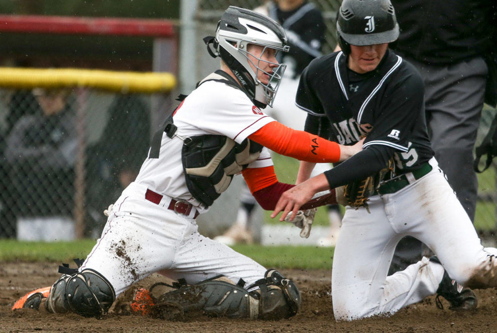 Cascade’s Nicholas Klemp (left) tags out Jackson’s Diego Altamirano during a game on April 11, 2018, at Cascade High School in Everett. (Andy Bronson / The Herald)
