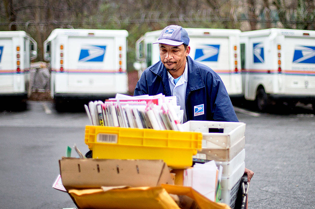 A U.S. Postal Service letter carrier gathers mail to load into his truck before making his delivery run.. After weeks of railing against online shopping giant Amazon, President Donald Trump signed an executive order Thursday to create a task force to study the United States Postal Service. (Dave Goldman / AP Photo)