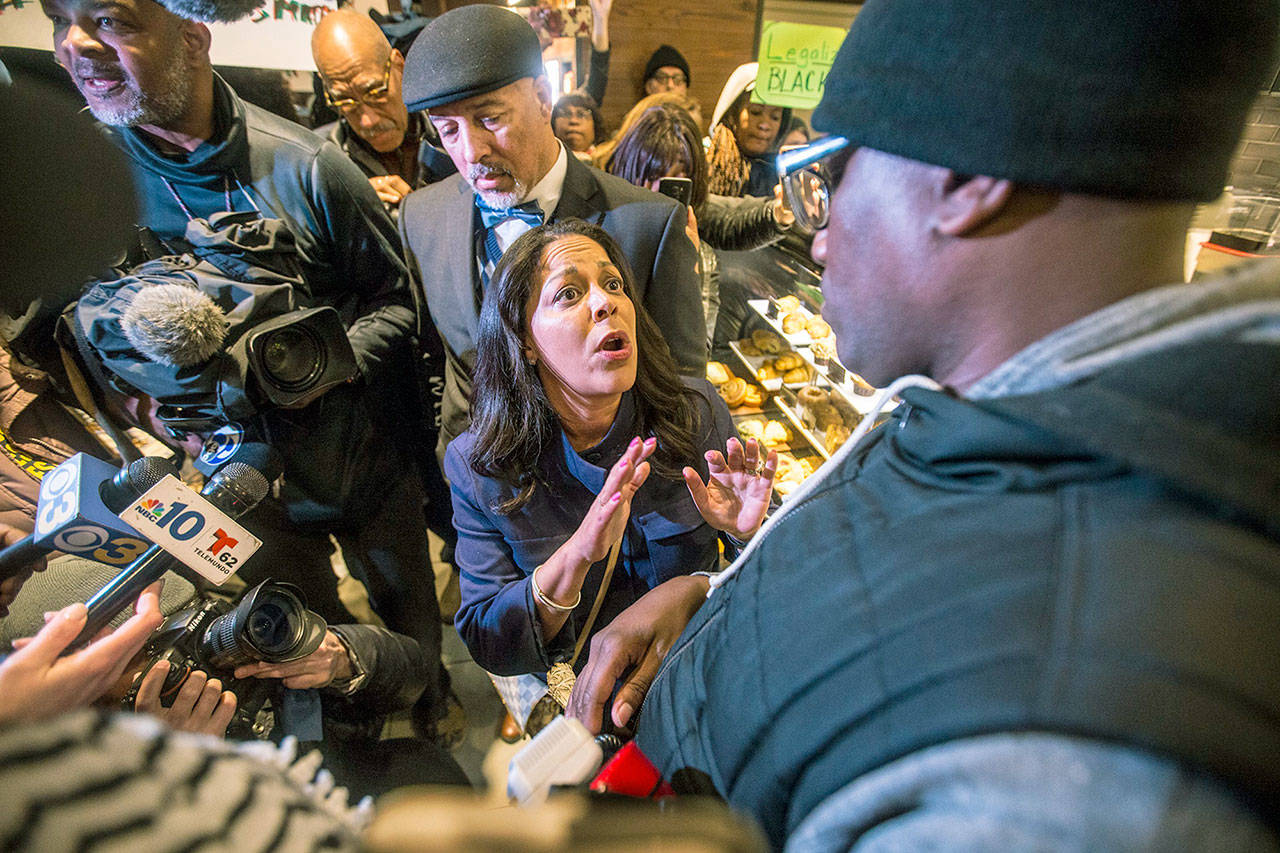 Camille Hymes (center), regional vice president of Mid-Atlantic operations for Starbucks Coffee, speaks with Asa Khalif of Black Lives Matter (right) after protesters entered the coffee shop on Sunday. (Mark Bryant/The Philadelphia Inquirer via AP)