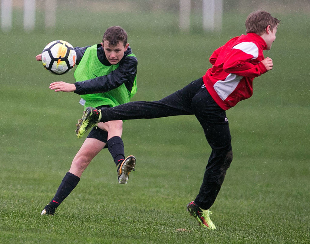 Alden Pate (left) kicks a ball while Gabriel Esterly defends during a Snohomish Youth Soccer Club Developement Academy scrimmage on April 5 at Stocker Fields in Snohomish. (Kevin Clark / The Herald)
