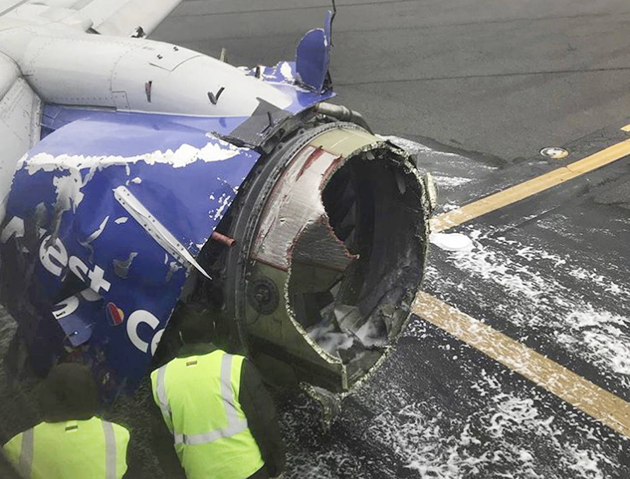 The engine on a Southwest Airlines plane is inspected as it sits on the runway at the Philadelphia International Airport after it made an emergency landing in Philadelphia on Tuesday. (Amanda Bourman via AP)