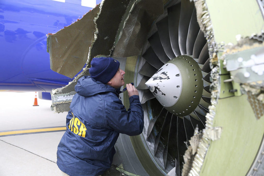 A National Transportation Safety Board investigator examines damage to the engine of the Southwest Airlines plane that made an emergency landing at Philadelphia International Airport in Philadelphia. (NTSB via AP)
