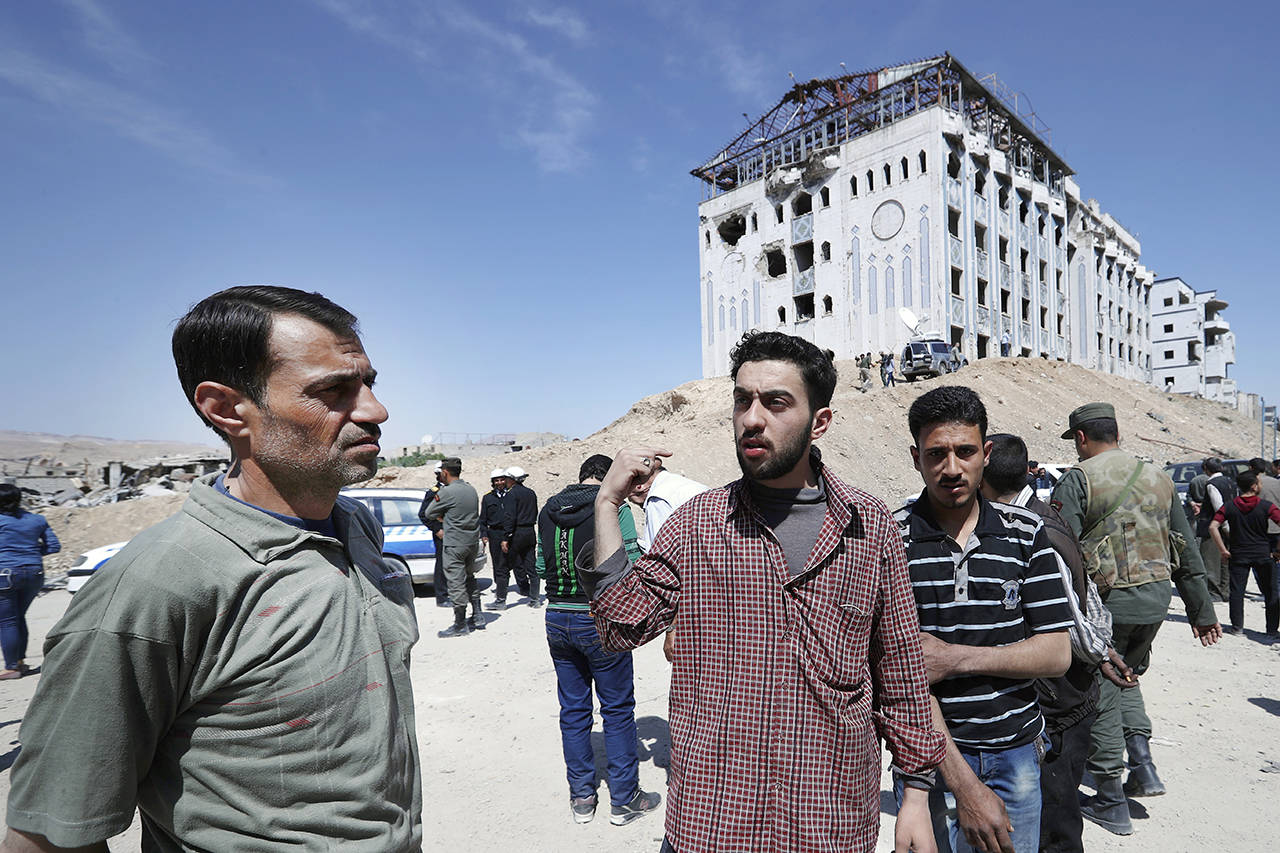 Kahled Mahmoud Nuseir, 25 (center), who lost his wife, Fatmeh Karout, who was nine months pregnant, and daughters, Qama, 18 months, and Nour, two and half years, during the alleged chemical weapons attack, speaks with the Associated Press in front of a hospital in the town of Douma. (AP Photo/Hassan Ammar)