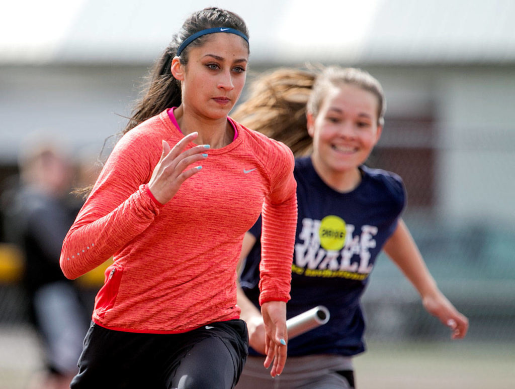 Monroe’s Kalea Funston (far right) prepares to hand off to Hannah Ganashamoorthy during a practice on April 18, 2018, at Monroe High School. (Kevin Clark / The Herald)
