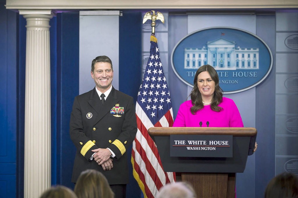 Sarah Huckabee Sanders, White House press secretary, speaks to members of the media while Ronny Jackson, physician for President Donald Trump, smiles during a White House press briefing in Washington in January. (Al Drago/Bloomberg, file)
