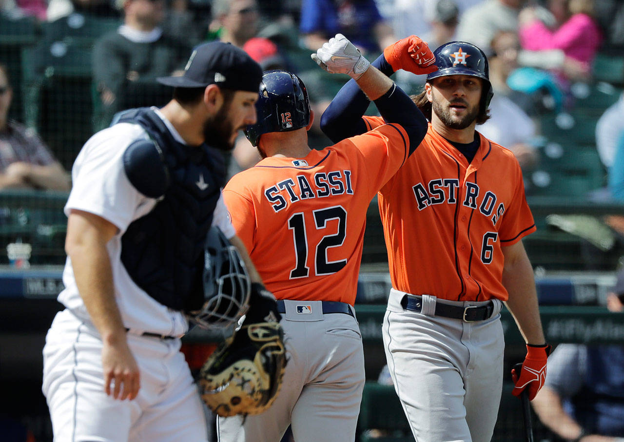 The Astros’ Max Stassi (12) is greeted at the plate by Jake Marisnick (right) as Mariners catcher David Freitas looks on after Stassi hit a solo home run in the seventh inning on April 19, 2018, in Seattle. (AP Photo/Ted S. Warren)