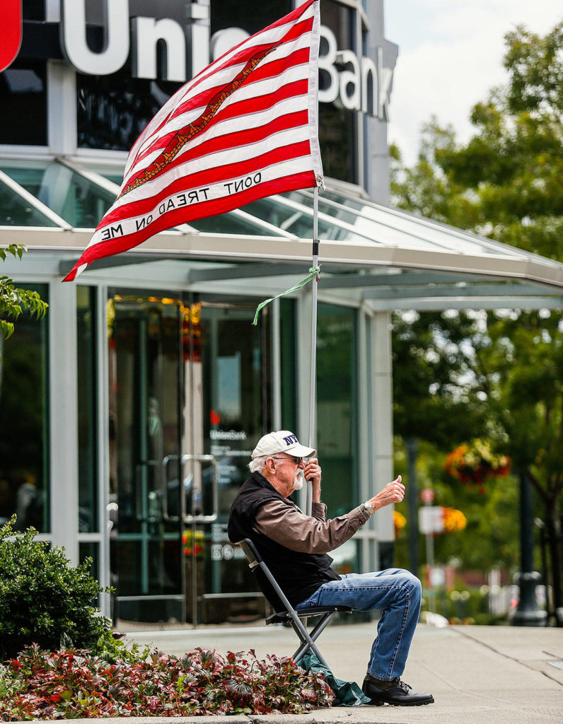 Air Force veteran John McKee, photographed at Hewitt and Colby in Everett July 8, 2016, died April 8. McKee, who served in Vietnam, and his wife, Audrey McKee, 80, were a regular Friday presence at the intersection with their flags and poster-size messages for years. Audrey continues to participate. (Dan Bates / Herald file)
