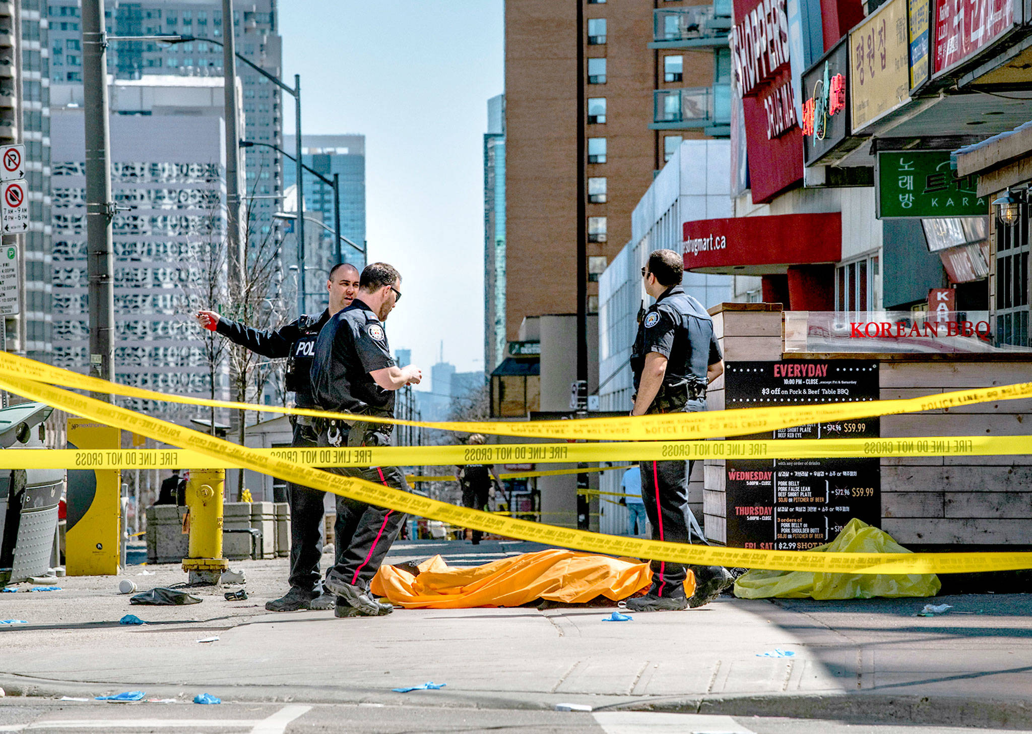 Police officers stand by a body covered on the sidewalk in Toronto after a van crashed into a crowd of pedestrians on Monday. (Aaron Vincent Elkaim/The Canadian Press via AP)