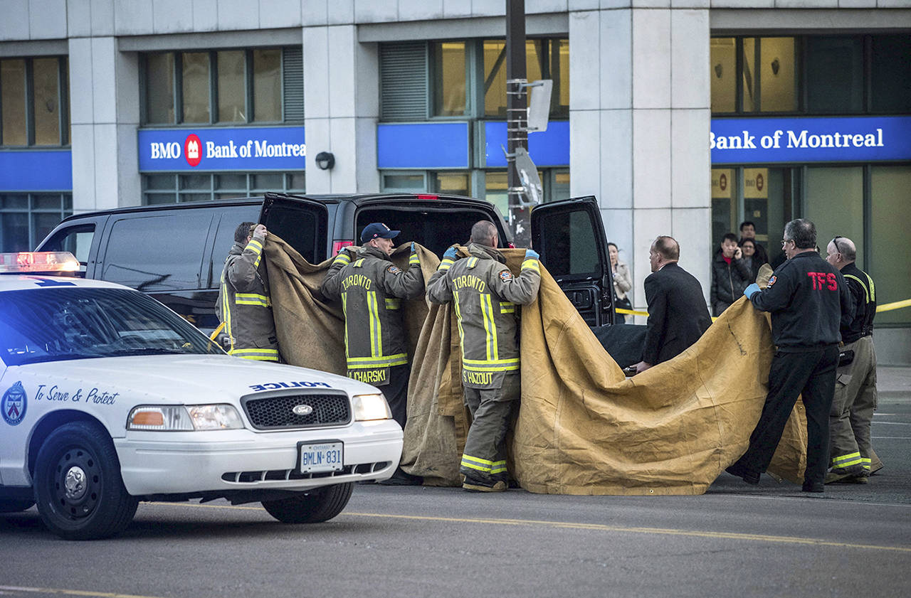 Officials carry a body into a vehicle after a van mounted a sidewalk crashing into pedestrians in Toronto on Monday. (Aaron Vincent Elkaim/The Canadian Press via AP)