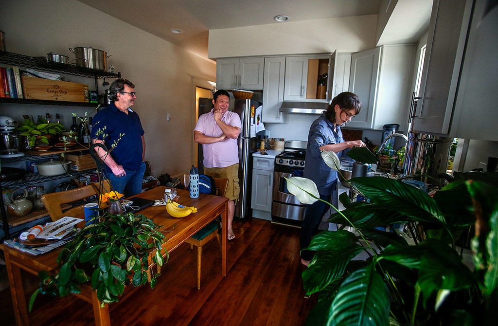 Gary Nelson (left) visits with renters Lewis Nelson and Jocelyn Sandberg in the kitchen of their new apartment at 2108 Rucker Ave. Gary Nelson’s family company restored the the large, old home that had been sitting empty for more than a decade. (Dan Bates / The Herald)
