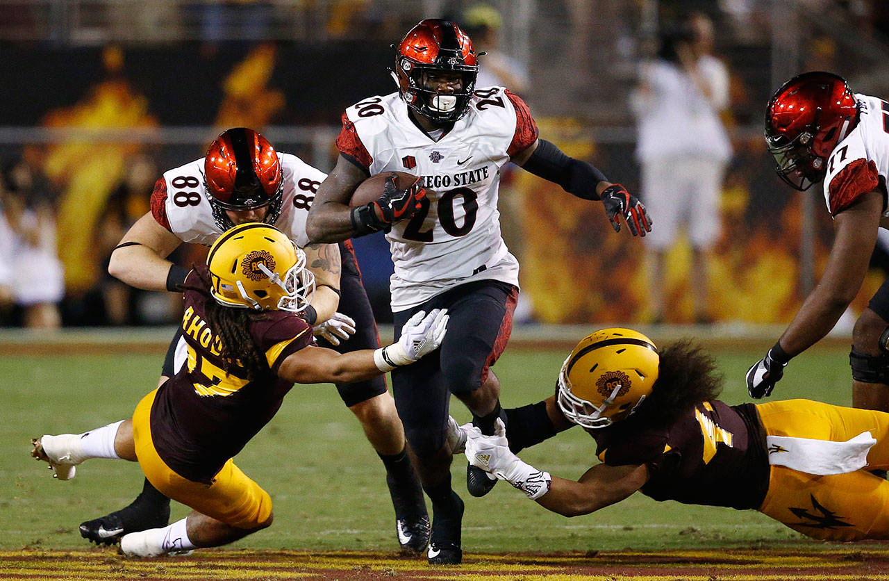 San Diego State’s Rashaad Penny (20) runs with the ball as Arizona State’s J’Marcus Rhodes (left) and Alani Latu move in to make the tackle during a game Sept. 9, 2017, in Tempe, Ariz. (AP Photo/Ross D. Franklin)