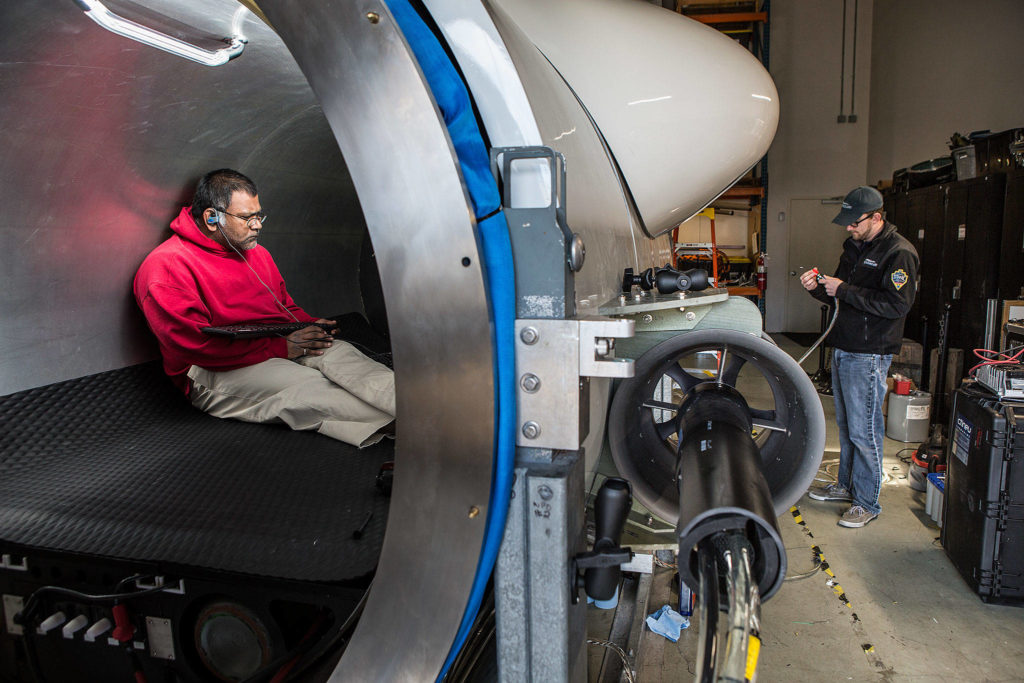 OceanGate engineer Mark Walsh programs control software as engineering technician Andrew Hawke installs a collars on a camera as they get the Titan submersible ready for testing. (Andy Bronson / The Herald)
