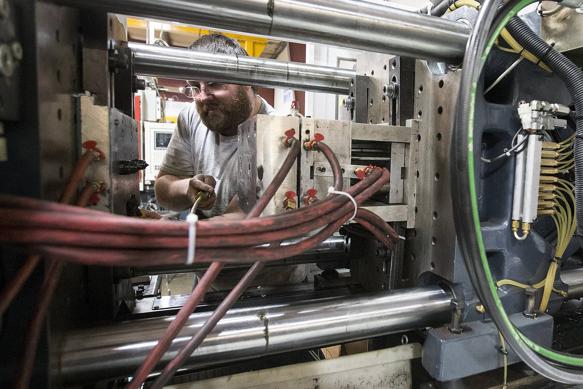 Chad Neece, an apprentice at Sea-Lect Plastics, sets up an injection molding machine at the company’s Everett factory. (Ian Terry / The Herald)