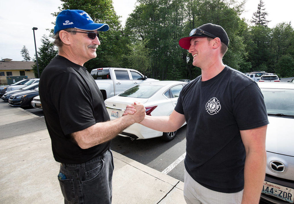 George Safadago embraces as Mukilteo Fire Department paramedic Brian Ouellette on their first meeting since Safadago’s heart attack, March 7, on a sidewalk near The Lodge Sports Grill, on Wednesday, May 9, in Mukilteo. (Andy Bronson / The Herald)
