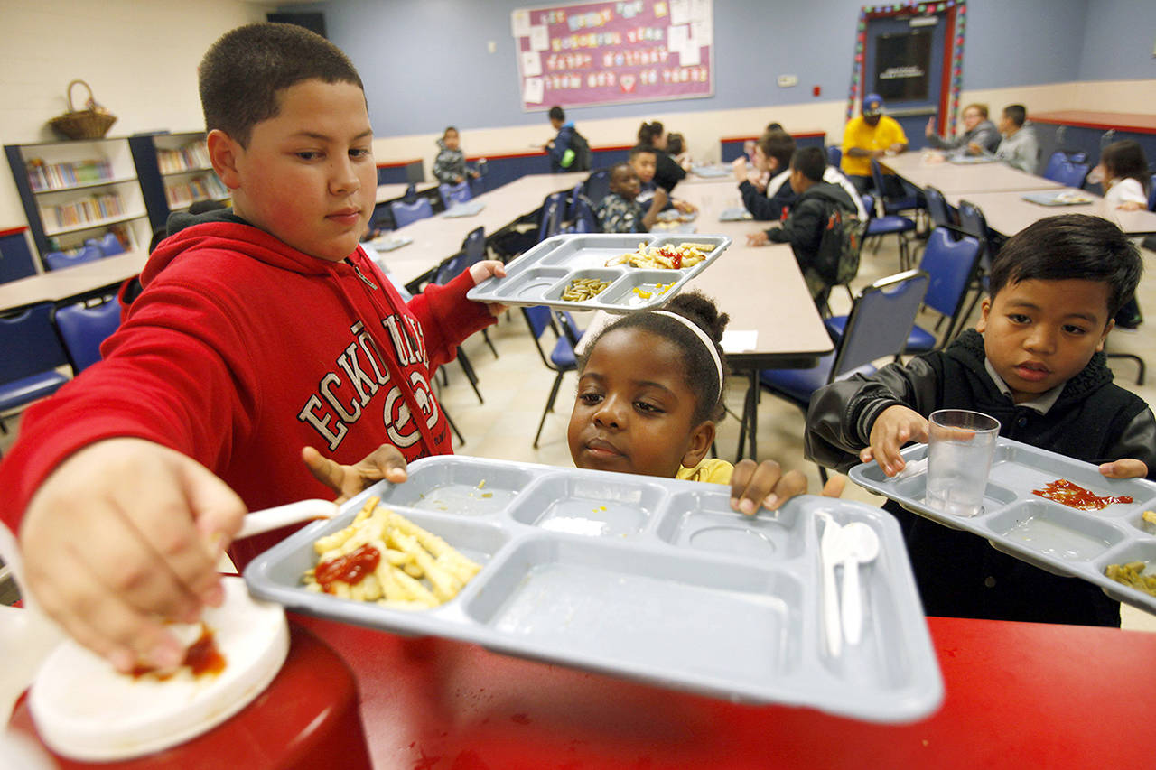 Keoni Diacan helps Risingsun Kalam put ketchup on her french fries as Donald Keju Jr. looks on during a 2015 dinner at the Everett Boys & Girls Club. (Herald file)
