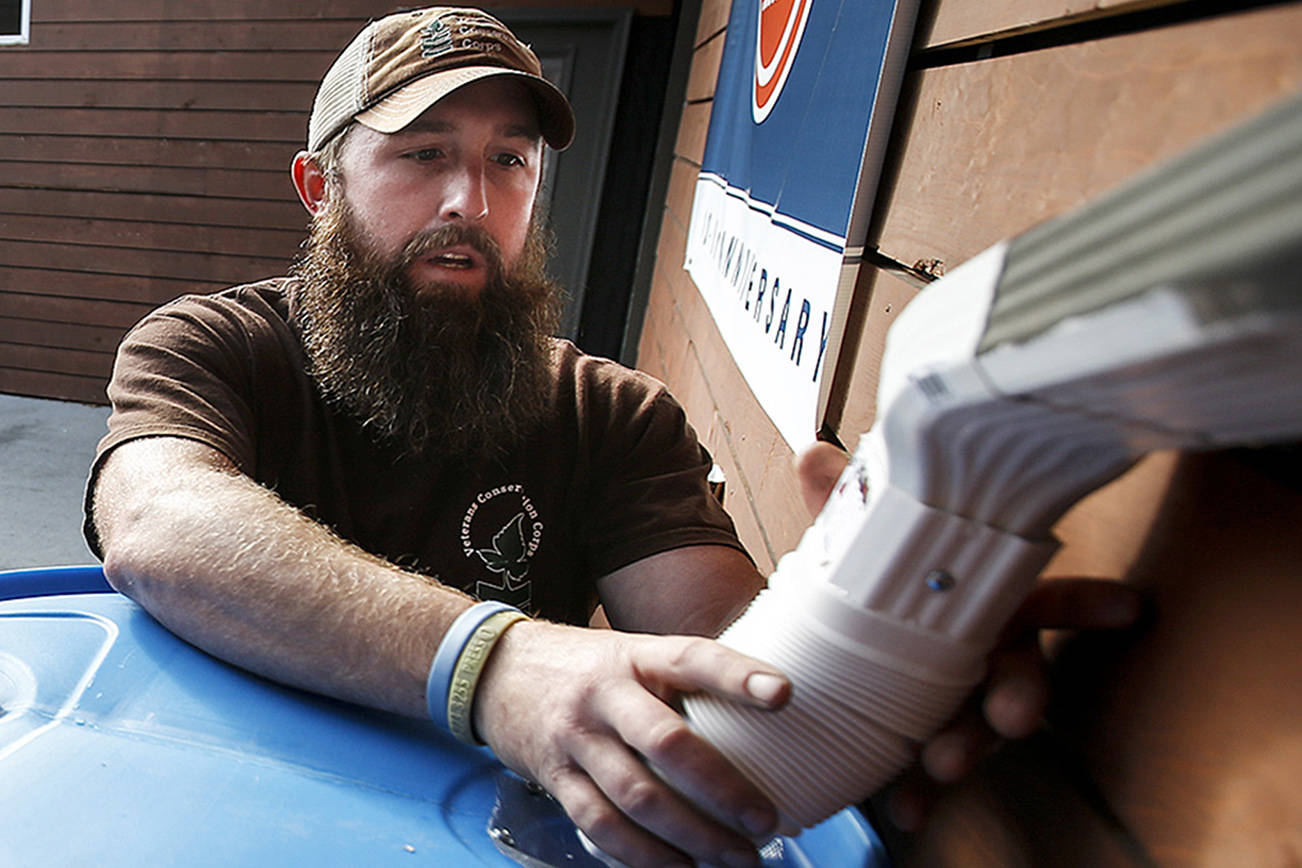 Ian Terry / The Herald Matt Cash (left) and Taylor Pesce work to install a rain barrel at Experience Momentum in Lynnwood on Wednesday, Oct. 11. Cash and Pesce work along with other veterans in a group that completes projects around the county for the Snohomish Conservation District. Photo taken on 10112017