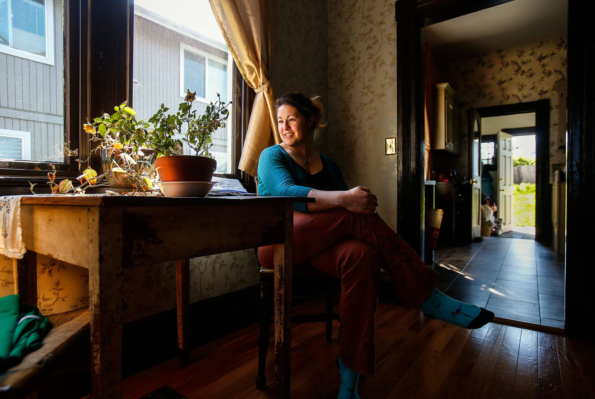 Andee Vaughan, 36, who loves old houses and rents this one, enjoys the play of sunlight Monday in the Swalwell Cottage. Said to be Everett’s oldest standing house, it was completed in 1892, a year before the city was incorporated. (Dan Bates / The Herald)