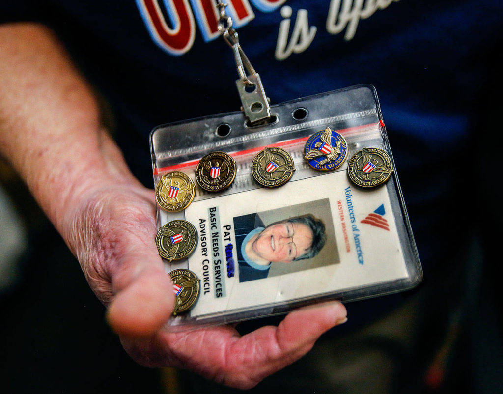 Volunteer Pat Reeve, 78, has seven pins on her VOA identification card for helping many hours. (Dan Bates / The Herald)
