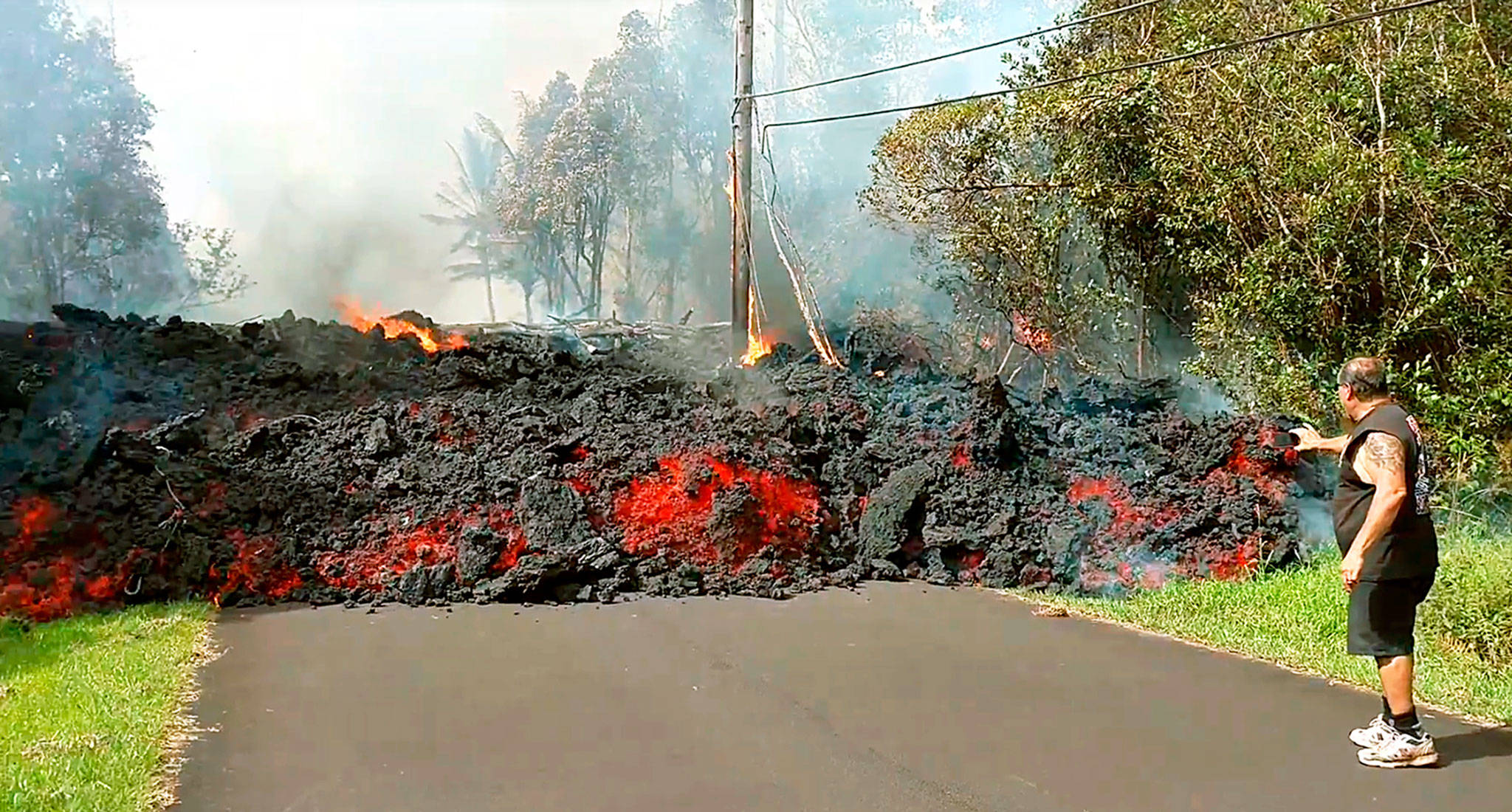An unidentified man gets close to a lava flow advancing down a road in the Leilani Estates subdivision near Pahoa on the island of Hawaii on Monday. (Scott Wiggers/Apau Hawaii Tours via AP)