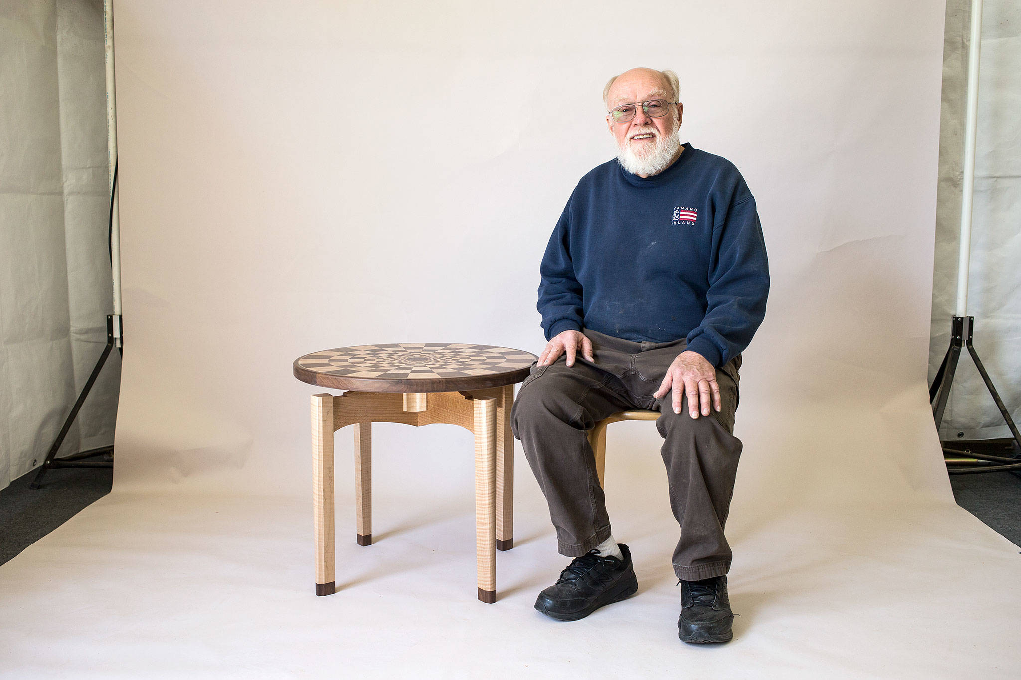 Woodworker Russ Riddle with an illusion table in a photo studio in his shop on Camano Island. Riddle is well know for his marquetry woodwork and will host visitors to his shop during the Camano Island studio tour. (Andy Bronson / The Herald)