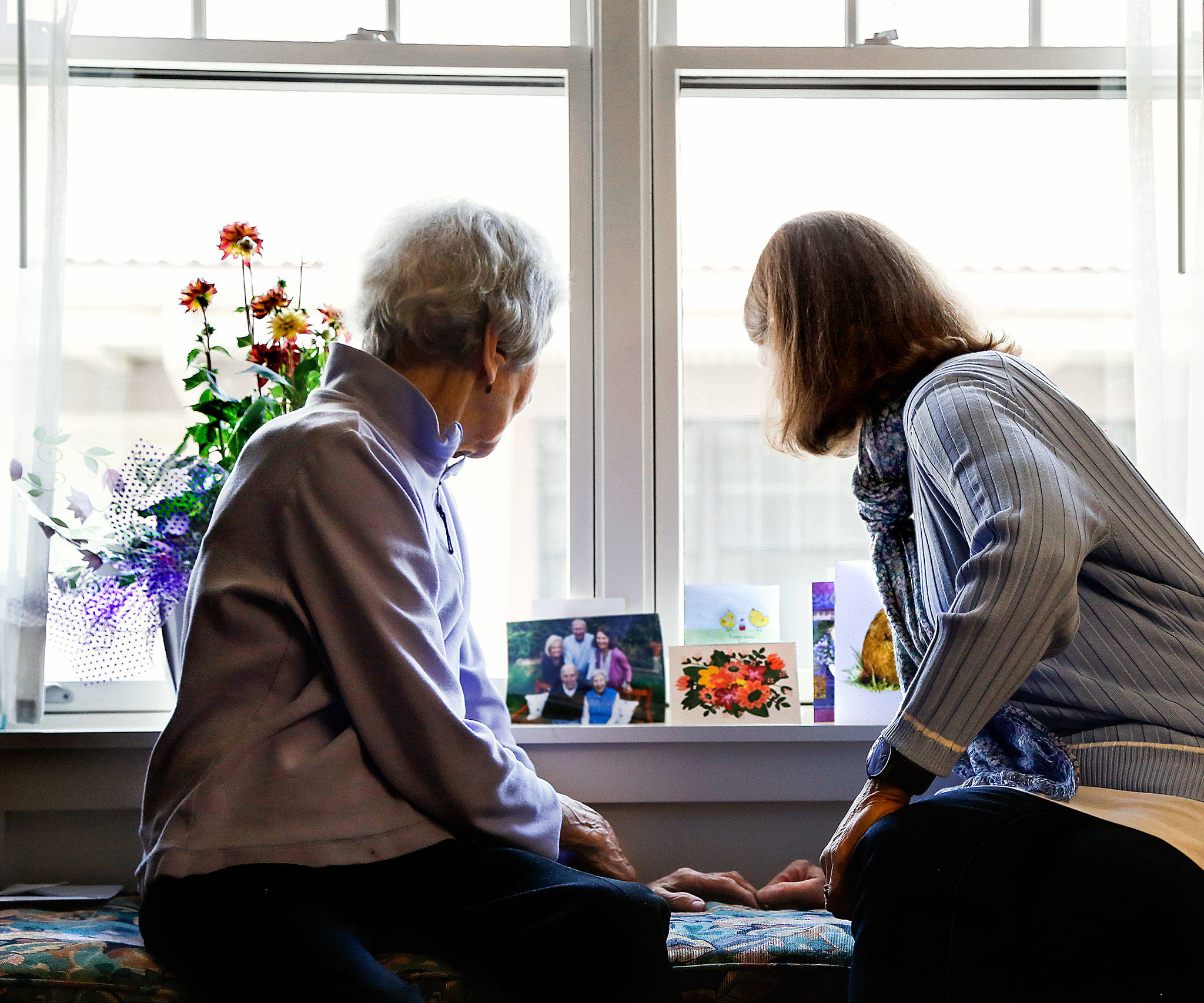 Julie Muhlstein looks at cards and pictures with her 96-year-old mother recently in her mom’s room at a Spokane retirement community. (Dan Bates / The Herald)