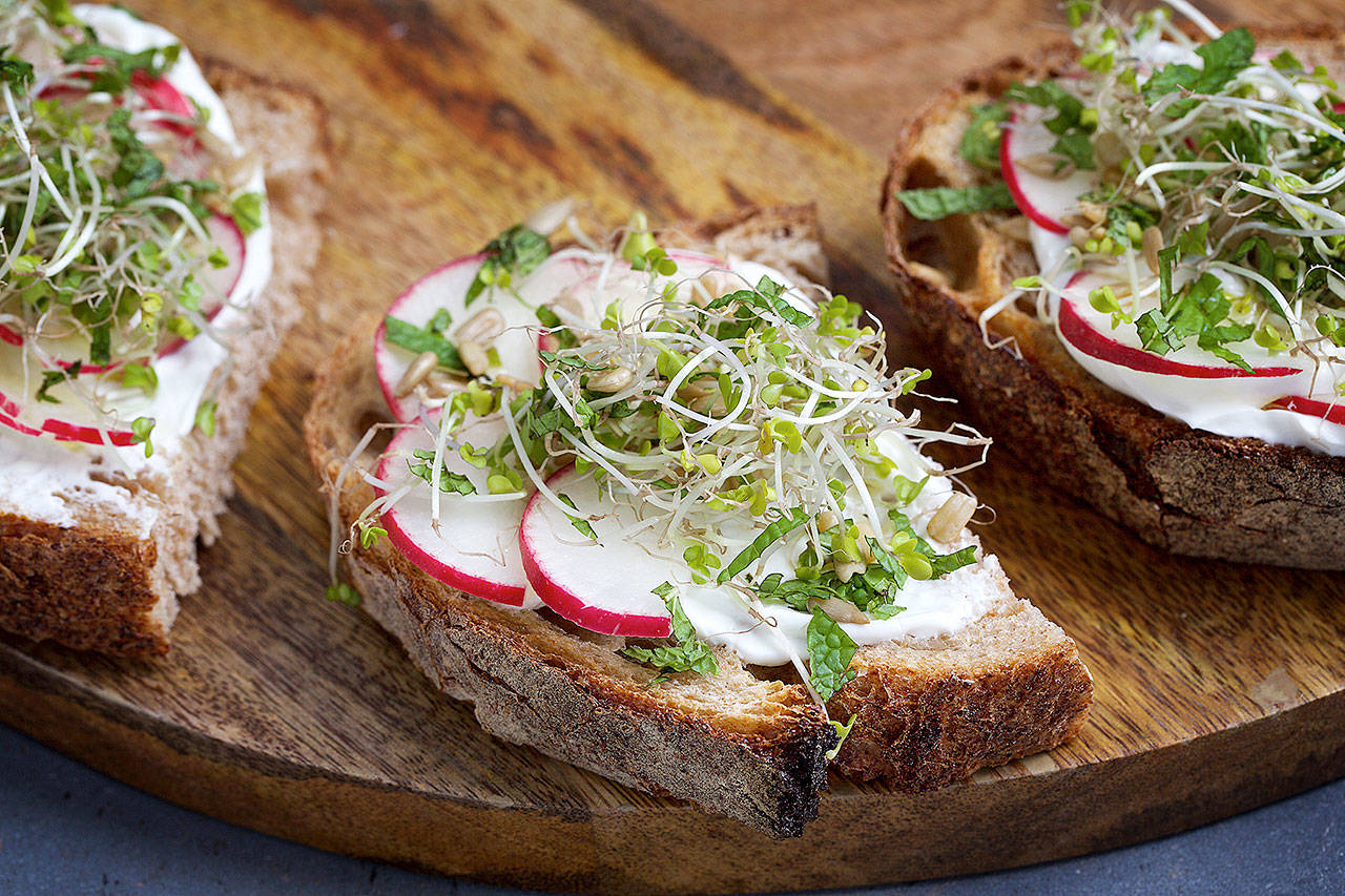 Spring toasts with labneh (a spreadable Middle Eastern yogurt) are topped with radish slices, sprouts and fresh mint leaves. (Photo by Deb Lindsey for The Washington Post)