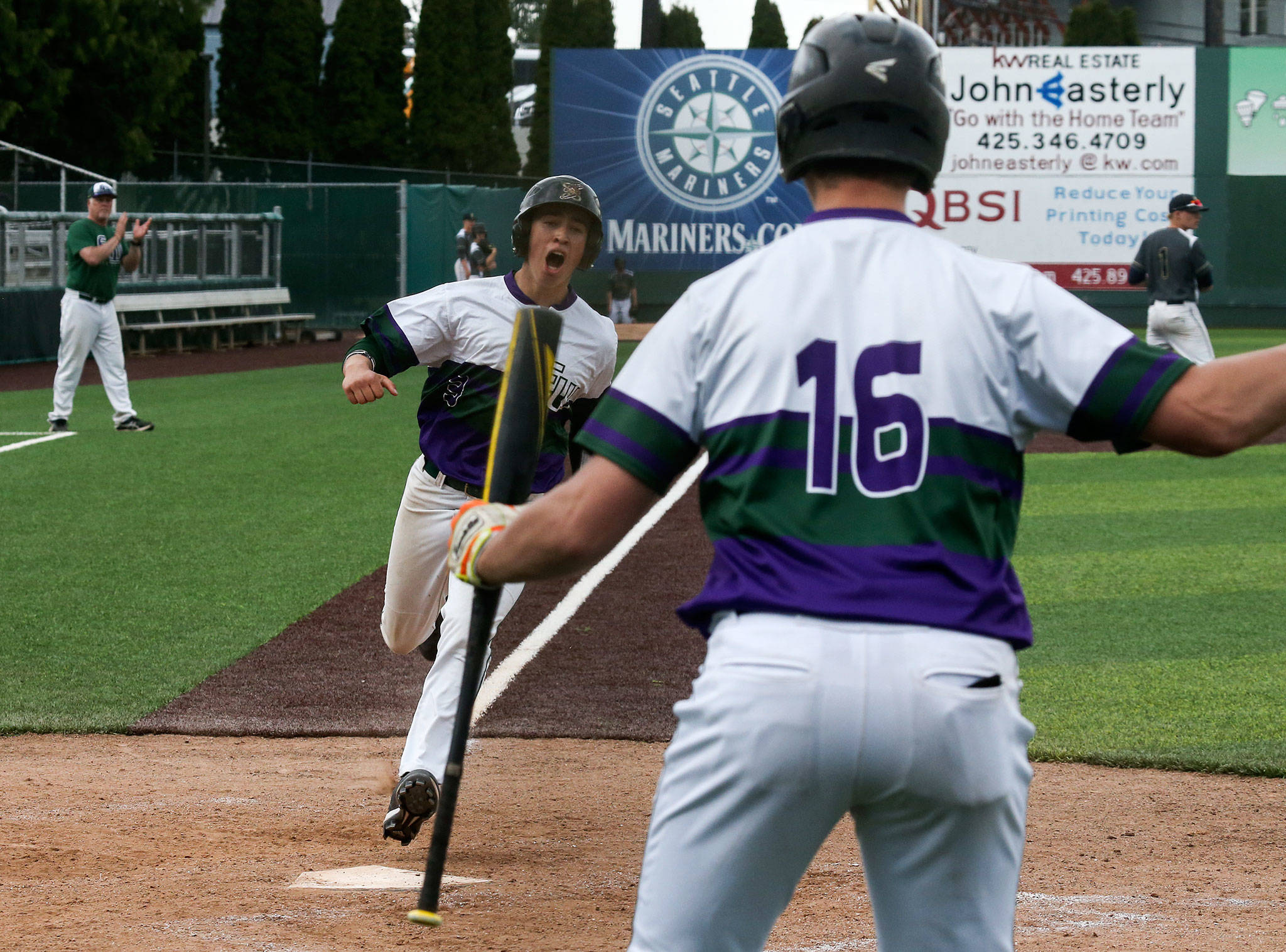 Edmonds-Woodway’s Sam Alvarado yells as he crosses home plate in front of teammate Thomas Blahous on Tuesday. The Warriors beat Arlington 3-0 in a 3A District 1 semifinal at Everett Memorial Stadium. (Andy Bronson / The Herald)