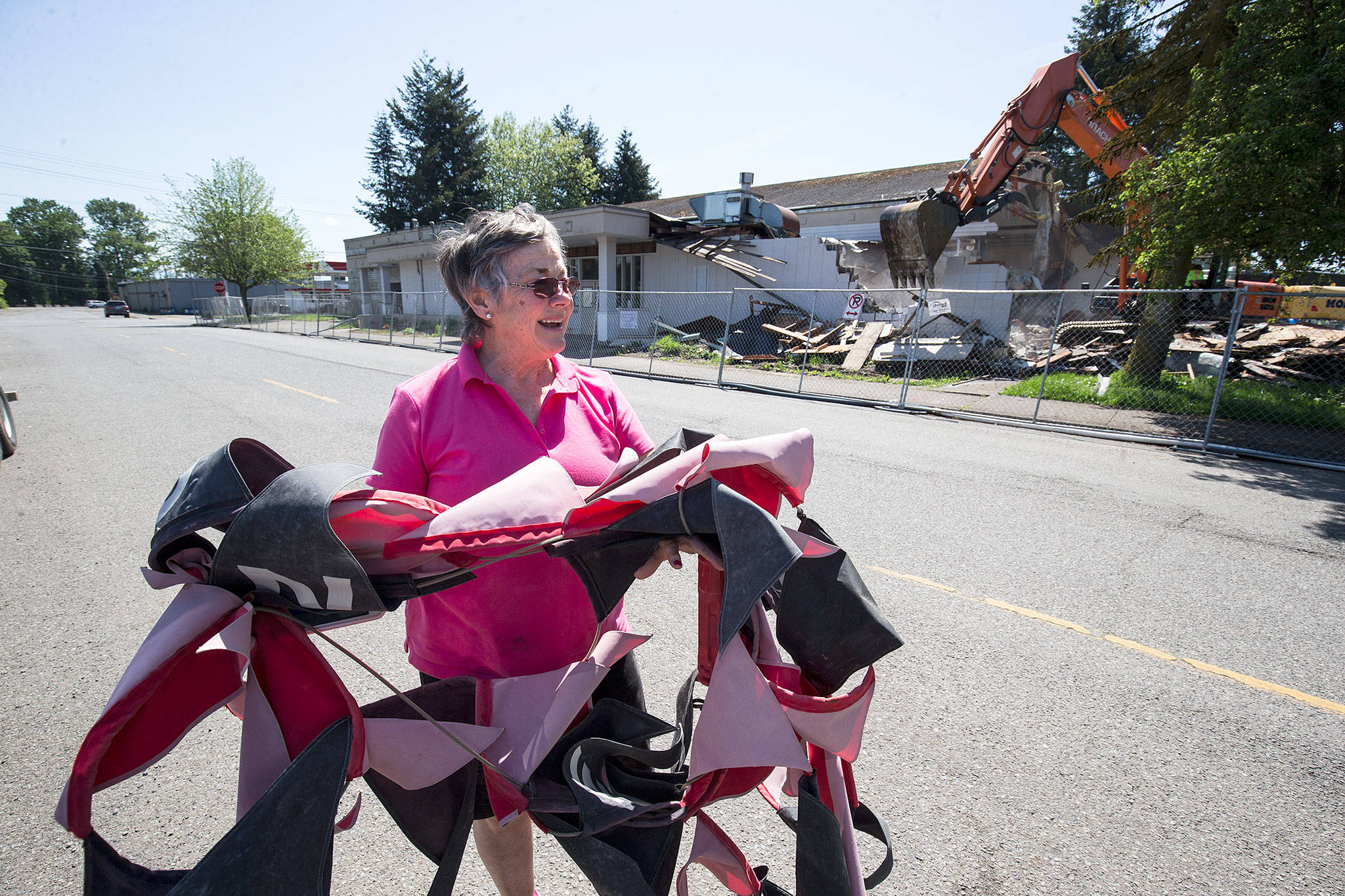 Rita Husmann smiles as she shows of the recovered banner given to her while North Hill Resouces crews demolish the Hal Moe Pool on Monday in Snohomish. Husmann says her kids all swam at the there and she got her lifesaving certificate at the pool. (Andy Bronson / The Herald)
